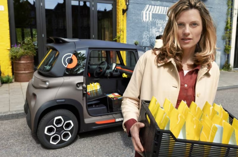 car in the background woman carrying a crate