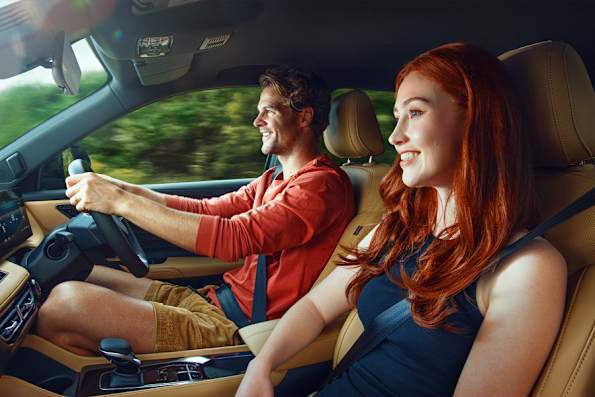 Two people smiling while driving in a car.