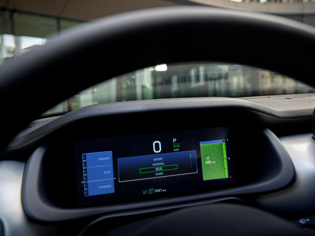 Close-up of a car's digital dashboard displaying driving modes and speed in kilometres per hour.