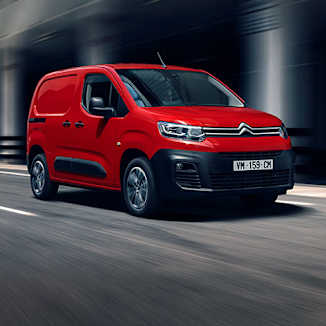 A red Citroën van driving on a road.