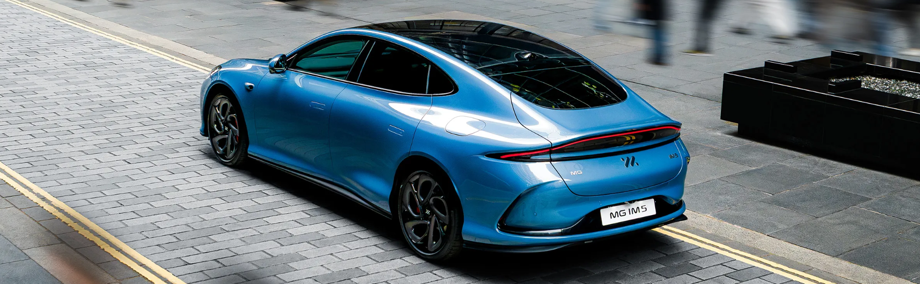 rear high shot of the back of a blue car on the street