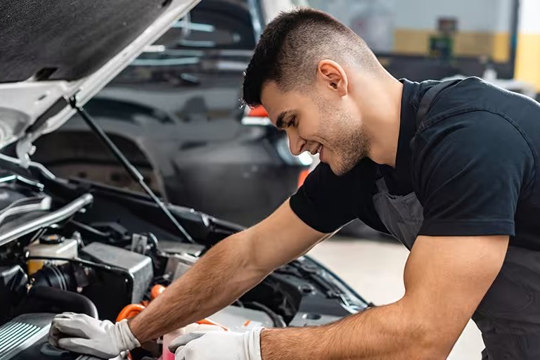 man looking at the engine of car